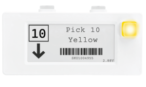 This image depicts a Voodoo Robotics multi-button device in white for display purposes. The actual device has a black case. The display asks the picker to pick 10 yellow items with the indicated SKU. On the left side, it shows the quantity 10 in a box and has an arrow indicating that the products are below.